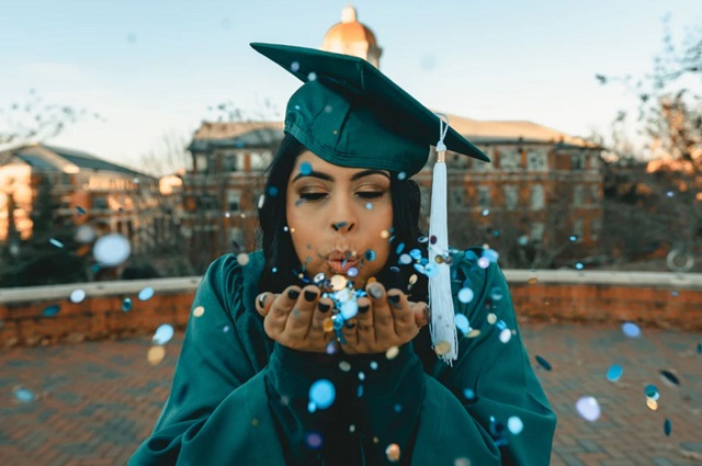 What Is a Universal Graduation Wish List? A girl in a graduation gown blowing confetti out of her hands.