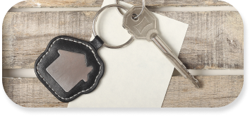 A single key sits on top of a piece of paper with a keychain that has the logo of a home.