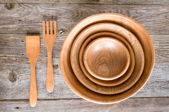 How to Set an Artisan Table, a table set with a large wodden fork and spreader as well as a set of different sized wooden bowls.
