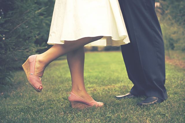 10 Great Gift Ideas for the Bride-to-be, a young woman in a white dress and a young man in suit pants standing outside in the grass.